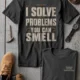 Funny Plumber Repair Graphic Tee "I Solve Problems You Can Smell" Back - "Plumbing Systems Diagnostician" Front — pepper — Flat-lay Funny Plumber Repair Graphic Tee "I Solve Problems You Can Smell" Back - "Plumbing Systems Diagnostician" Front — pepper t-shirt, flat-lay product photo | Pressure Tested Co