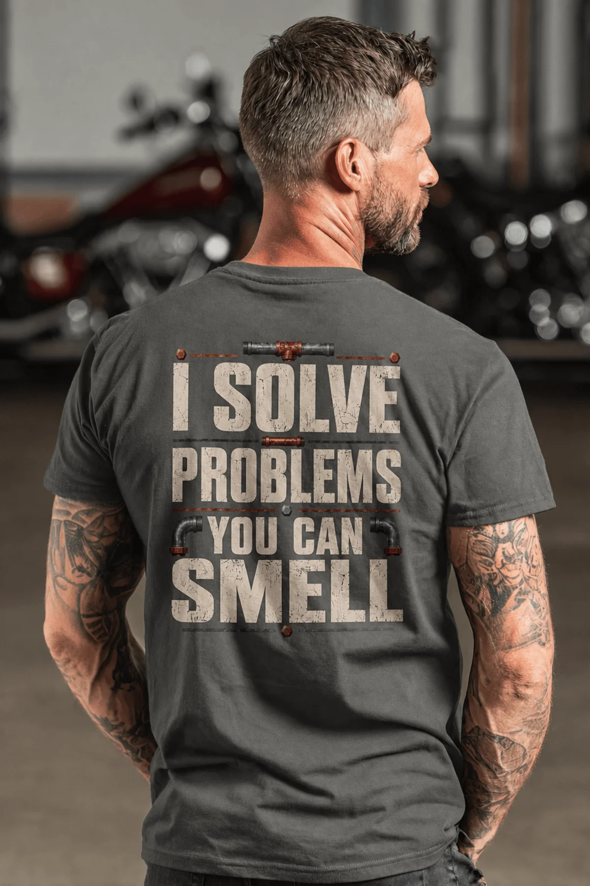 Funny Plumber Repair Graphic Tee "I Solve Problems You Can Smell" Back - "Plumbing Systems Diagnostician" Front — pepper — Model Funny Plumber Repair Graphic Tee "I Solve Problems You Can Smell" Back - "Plumbing Systems Diagnostician" Front — pepper t-shirt, model photo | Pressure Tested Co
