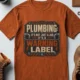 Plumbing Warning Label T-Shirt — Funny Plumber Shirt — autumn t-shirt, flat-lay product photo | Pressure Tested Co