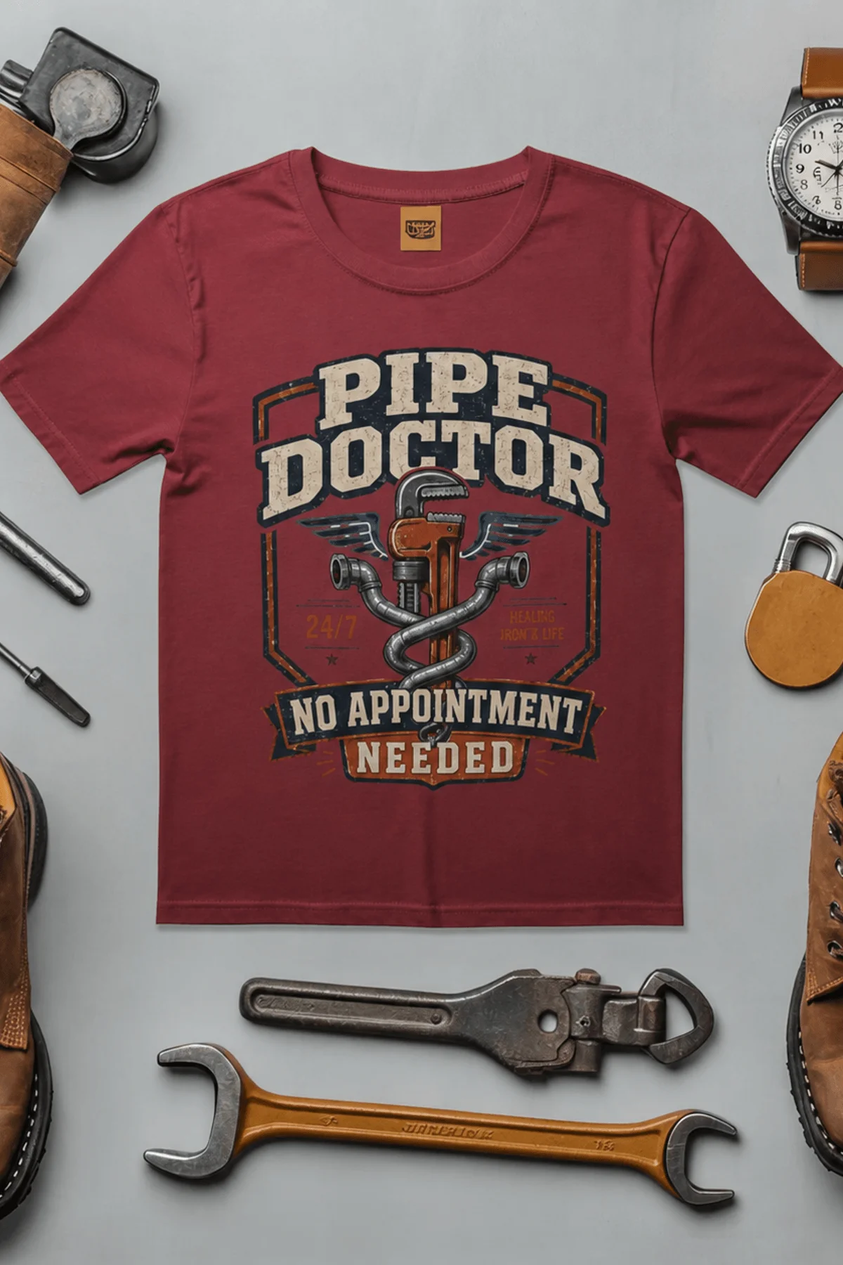 Plumber T-Shirt — "Pipe Doctor. No Appointment Needed" Vintage Work Shirt — chili — Flat-lay Plumber T-Shirt — "Pipe Doctor. No Appointment Needed" Vintage Work Shirt — chili t-shirt, flat-lay product photo | Pressure Tested Co