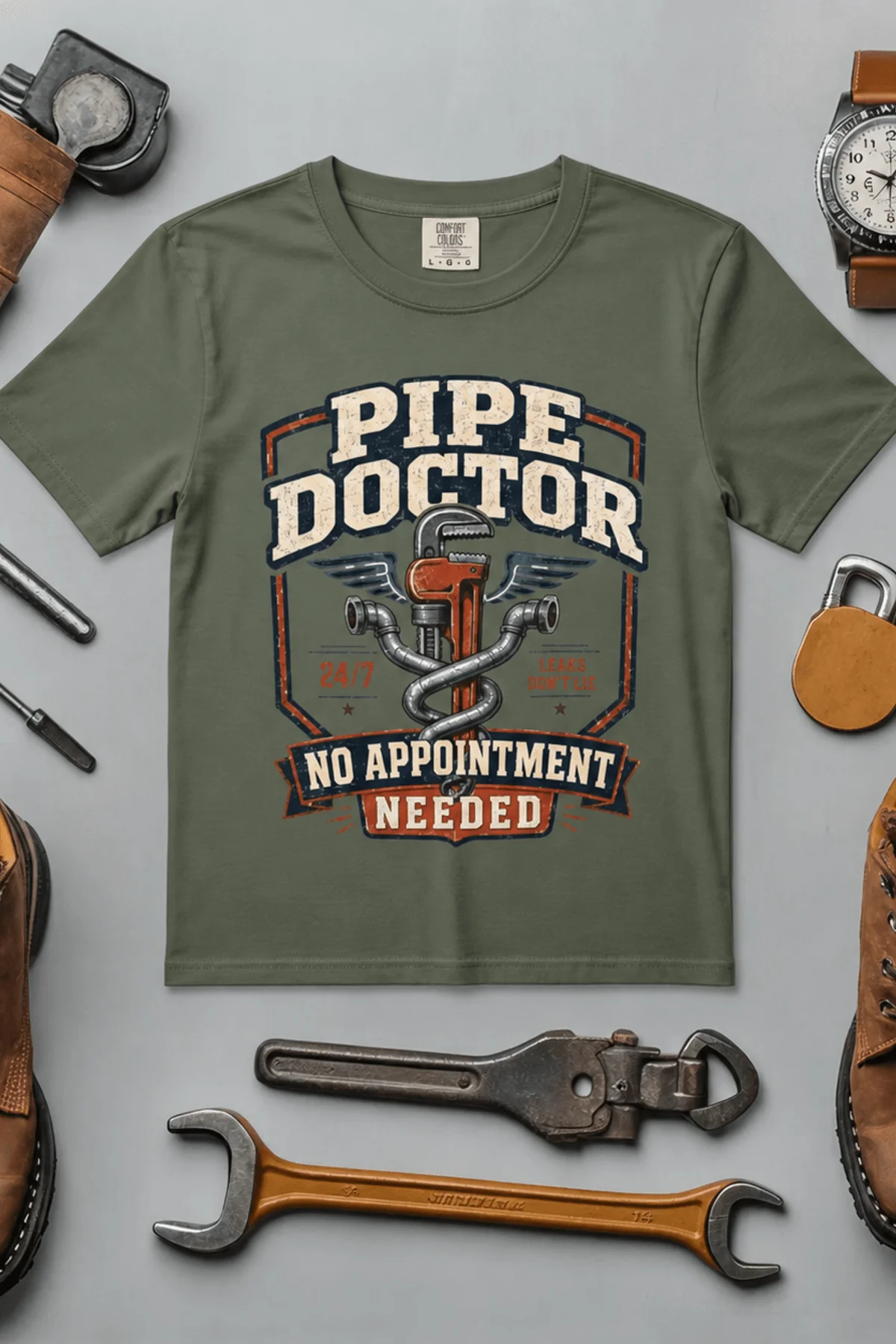 Plumber T-Shirt — "Pipe Doctor. No Appointment Needed" Vintage Work Shirt — moss — Flat-lay Plumber T-Shirt — "Pipe Doctor. No Appointment Needed" Vintage Work Shirt — moss t-shirt, flat-lay product photo | Pressure Tested Co