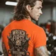 Wrench First Tee — "Wrench First, Questions Later" Mechanic Skull T-Shirt — orange t-shirt, model photo | Pressure Tested Co