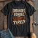 Grounded, Bonded and Slightly Tired Graphic Tee — Funny Electrical Worker Shirt — steel-blue t-shirt, flat-lay product photo | Pressure Tested Co