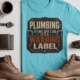 Plumbing Warning Label T-Shirt — Funny Plumber Shirt — turquoise t-shirt, flat-lay product photo | Pressure Tested Co