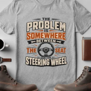 Driving Humor T-Shirt — "The Problem Is Somewhere Between The Seat And The Steering Wheel" — athletic-heather t-shirt, flat-lay product photo | Pressure Tested Co
