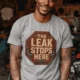 "The Leak Stops Here" Stop Sign Badge Style — Plumbing Repair Tech Humorous Tee — athletic-heather t-shirt, model photo | Pressure Tested Co
