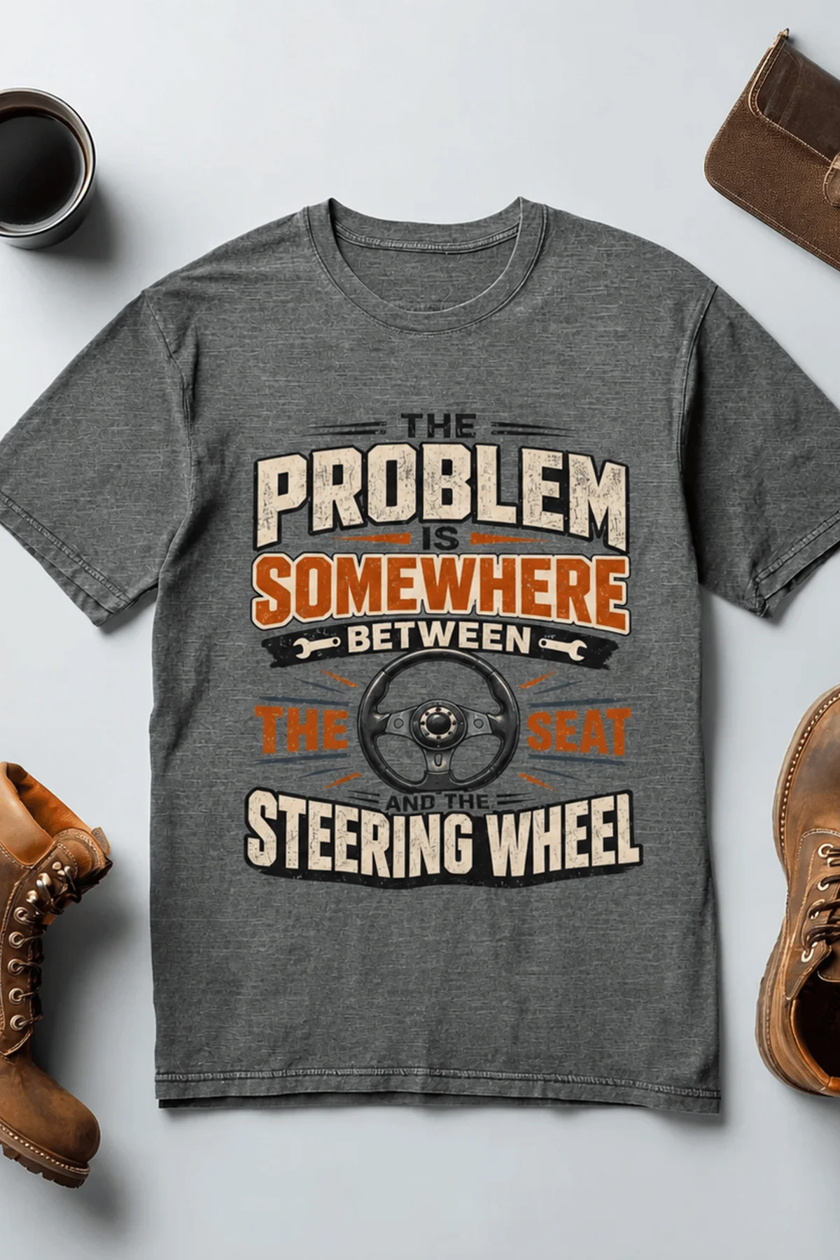 Driving Humor T-Shirt — "The Problem Is Somewhere Between The Seat And The Steering Wheel" — deep-heather t-shirt, flat-lay product photo | Pressure Tested Co