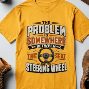 Driving Humor T-Shirt — "The Problem Is Somewhere Between The Seat And The Steering Wheel" — gold t-shirt, flat-lay product photo | Pressure Tested Co