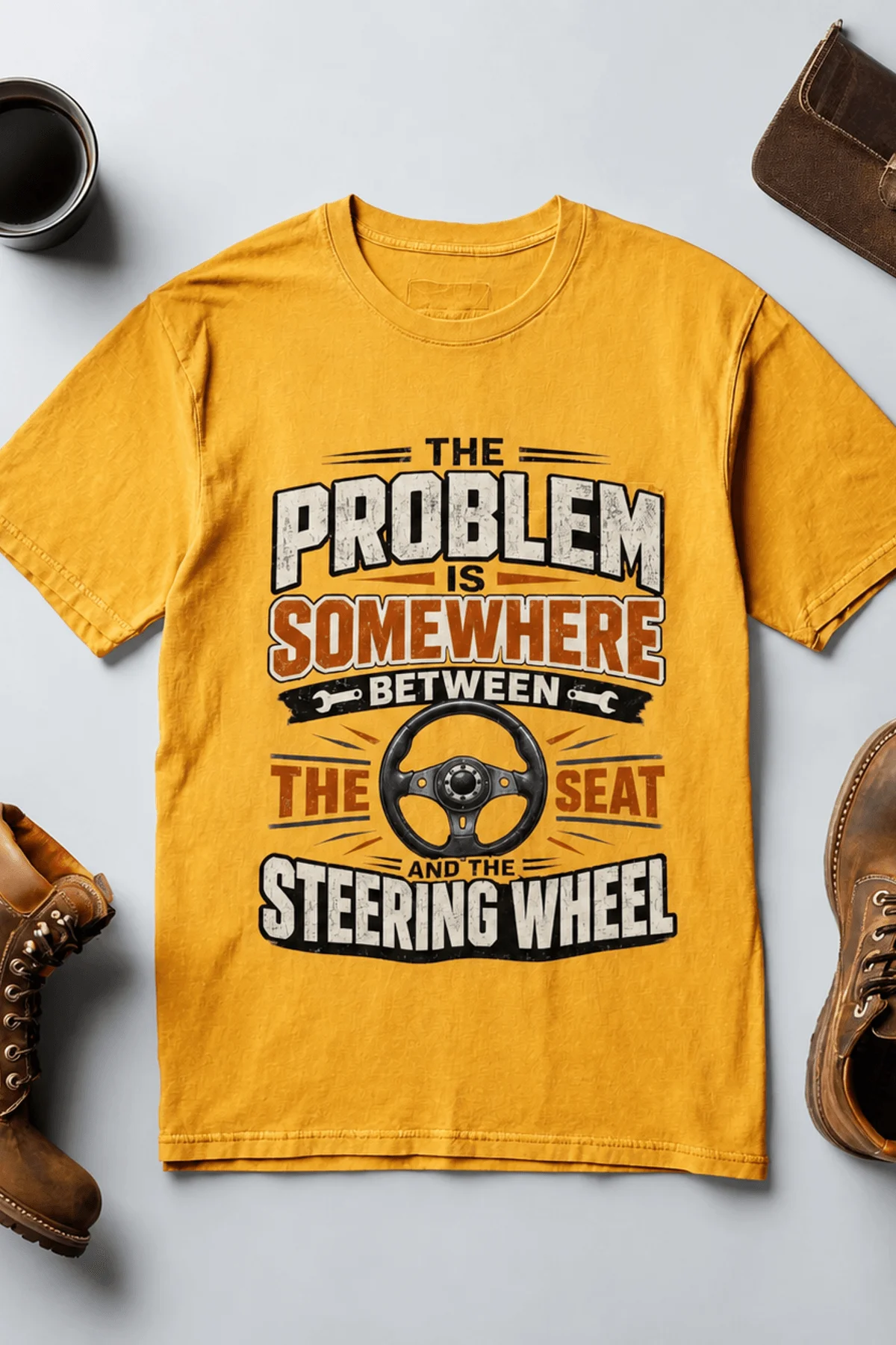 Driving Humor T-Shirt — "The Problem Is Somewhere Between The Seat And The Steering Wheel" — gold t-shirt, flat-lay product photo | Pressure Tested Co