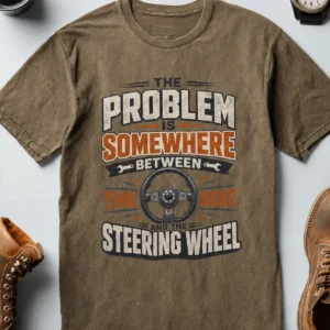 Driving Humor T-Shirt — "The Problem Is Somewhere Between The Seat And The Steering Wheel" — heather-olive t-shirt, flat-lay product photo | Pressure Tested Co
